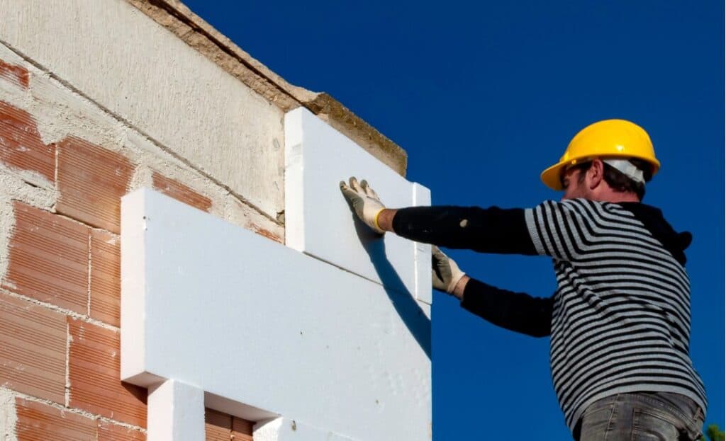 Instalador profesional instalando aislamiento térmico en fachada.