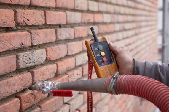 Aplicación de aislamiento insuflado URSA PUREFLOC en una pared de ladrillo mediante equipo profesional de insuflado.