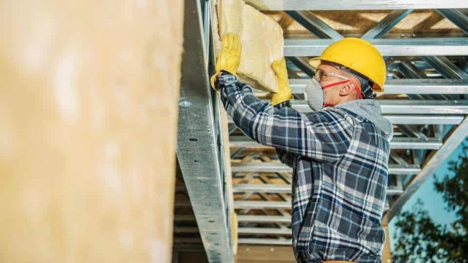 Instalador colocando aislamiento térmico en fachada durante una rehabilitación energética de vivienda.